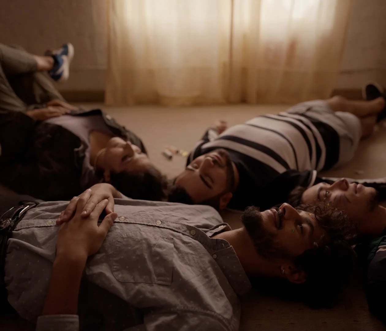 Several people lying on the floor with their heads together, laughing.
